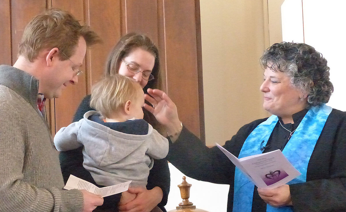 reverend martha with couple baptizing their baby